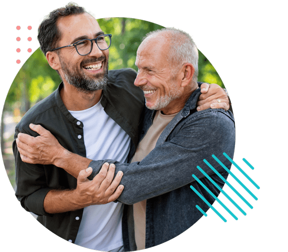 A man receives a hug from an older man as they laugh.